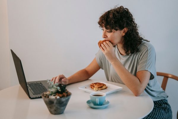 a woman eating and working on her laptop indoor setting