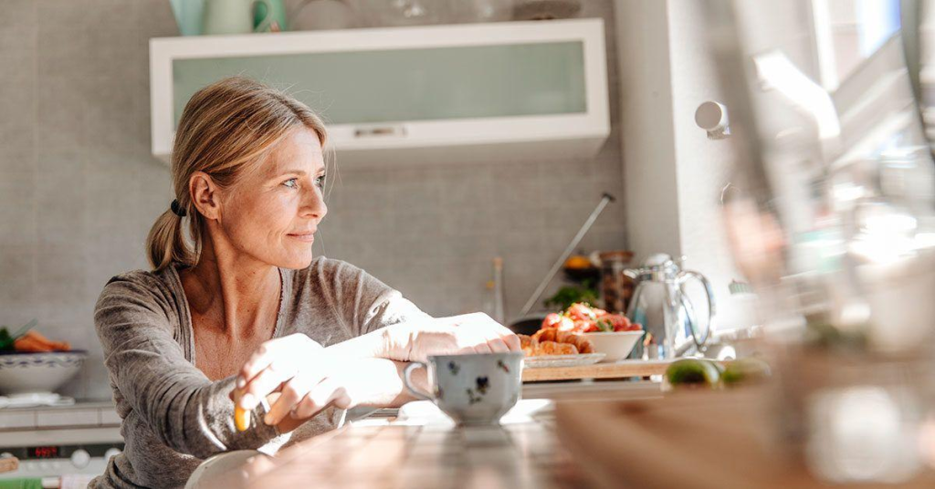 midlife woman at the kitchen table looking afar