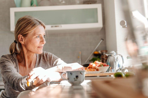 midlife woman at the kitchen table looking afar