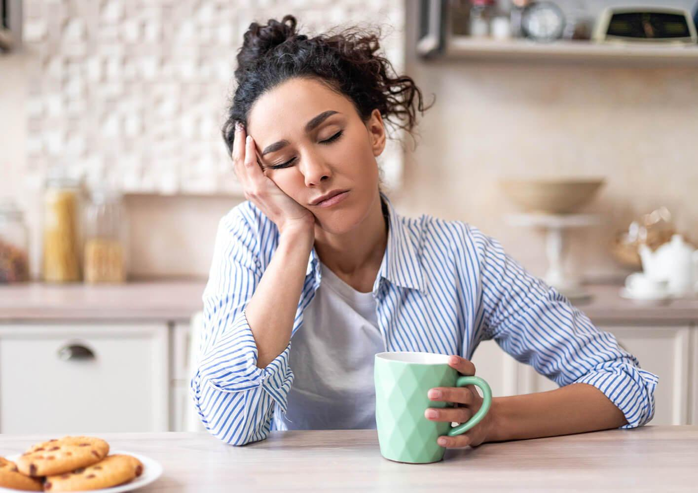 Woman sitting with a coffee, looking exhausted Woman sitting with a coffee, looking exhausted