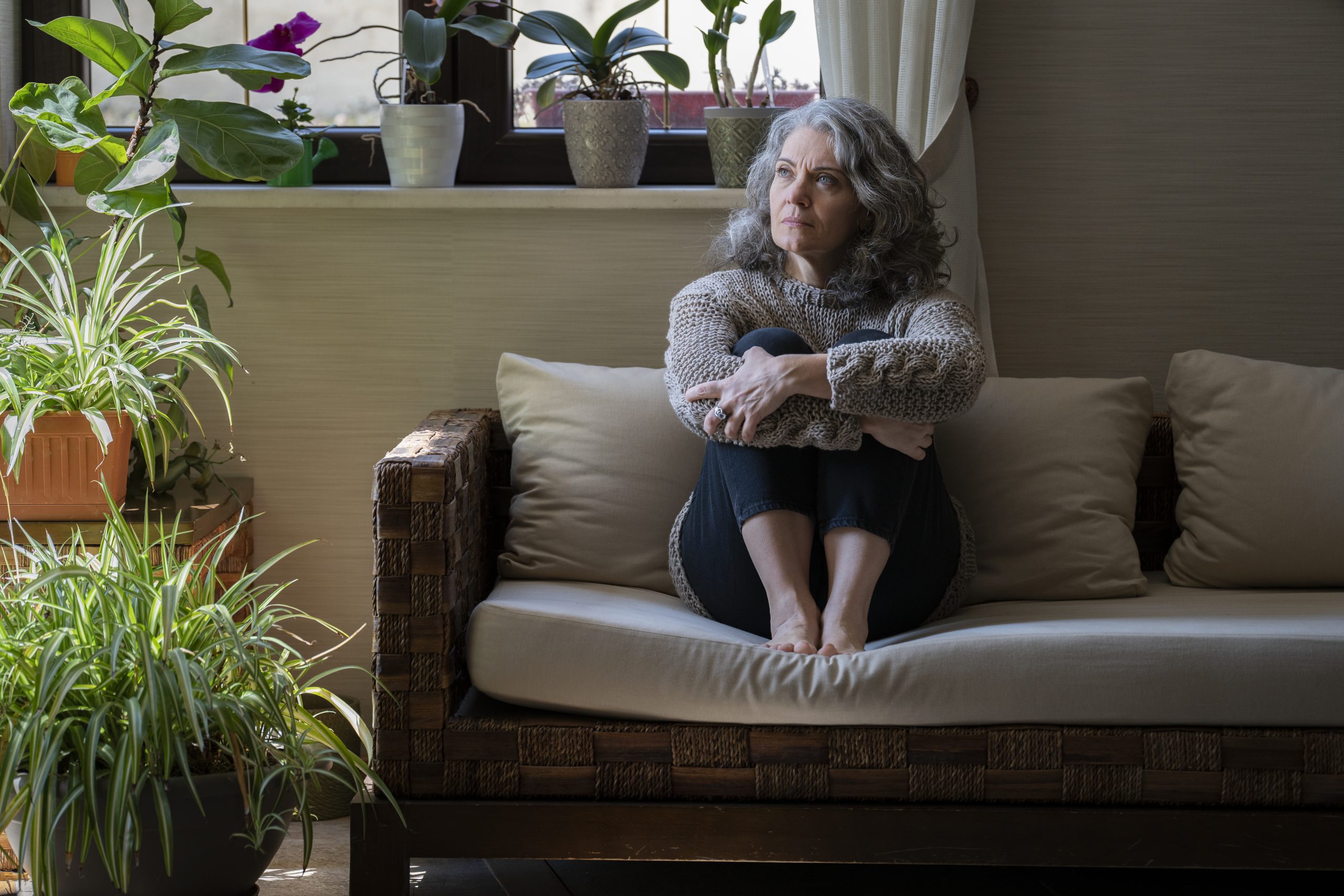 woman in her 40s–50s sitting comfortably looking thoughtful woman in her 40s–50s sitting comfortably looking thoughtful