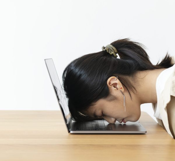 Stressed Asian girl resting her head on a laptop